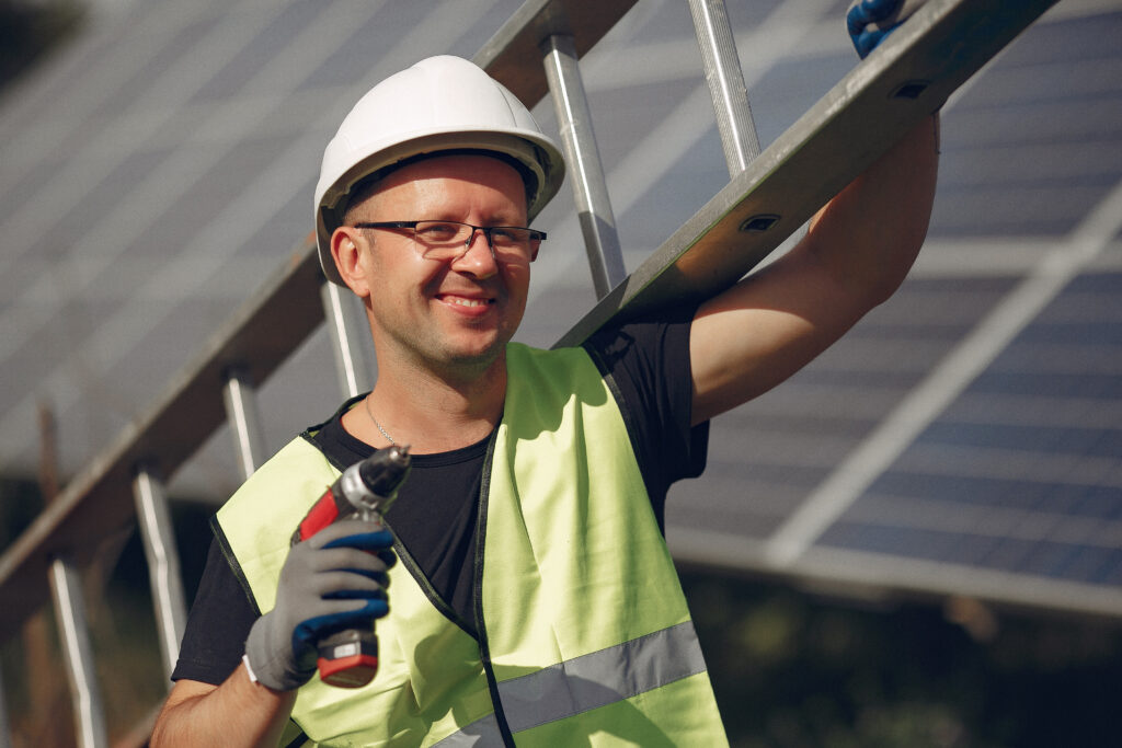 Engineer in a white helmet. Man near solar panel. Worker with a ladder